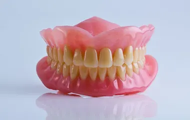 Custom-fit dentures shown with a smiling patient enjoying a beach town in Mexico, optimized for mobile view.